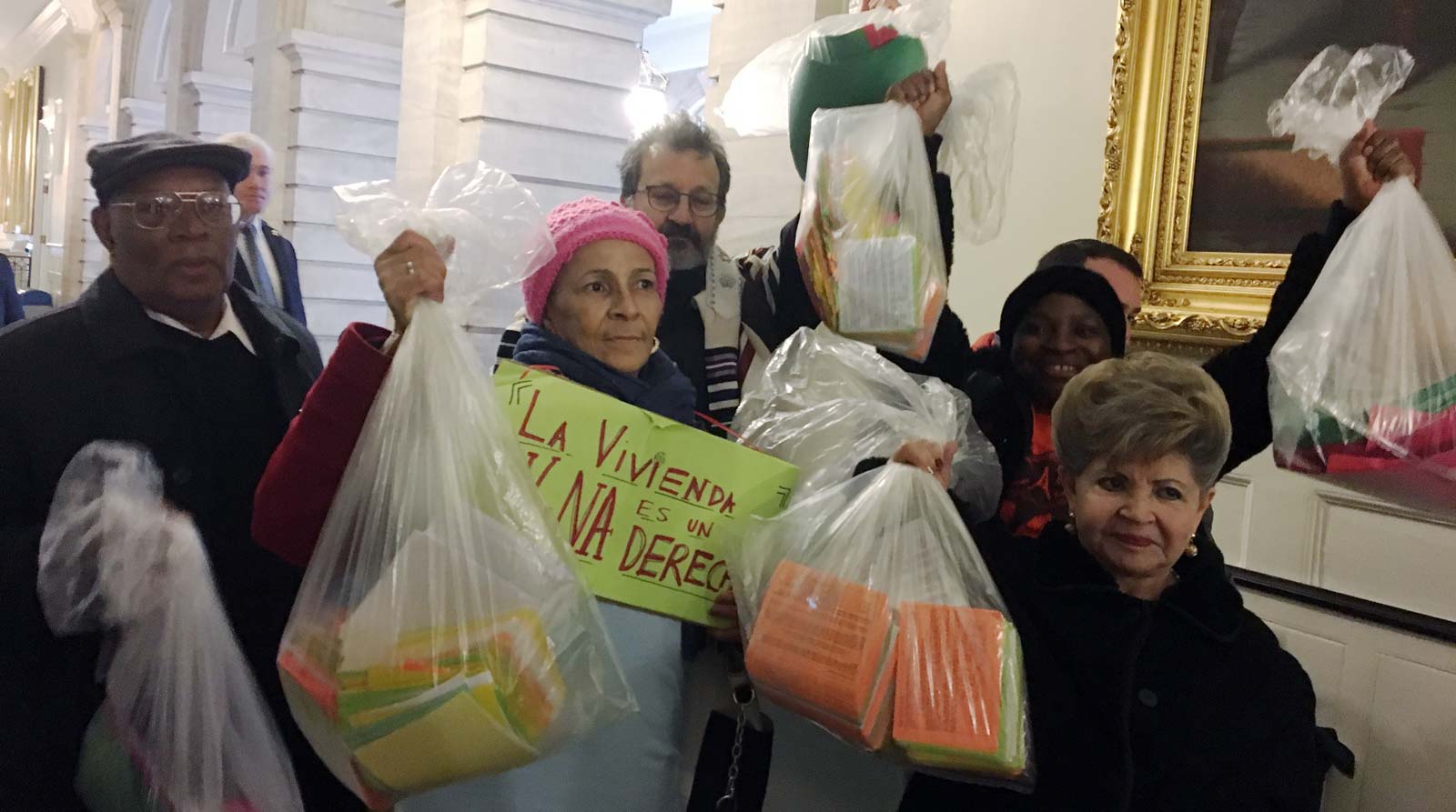 A group of Right to Counsel activists holds bags full of postcards demanding right to counsel